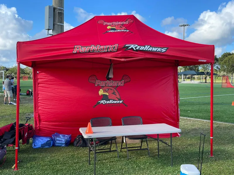 A red Redhawks tent with a registration table set up on the field
